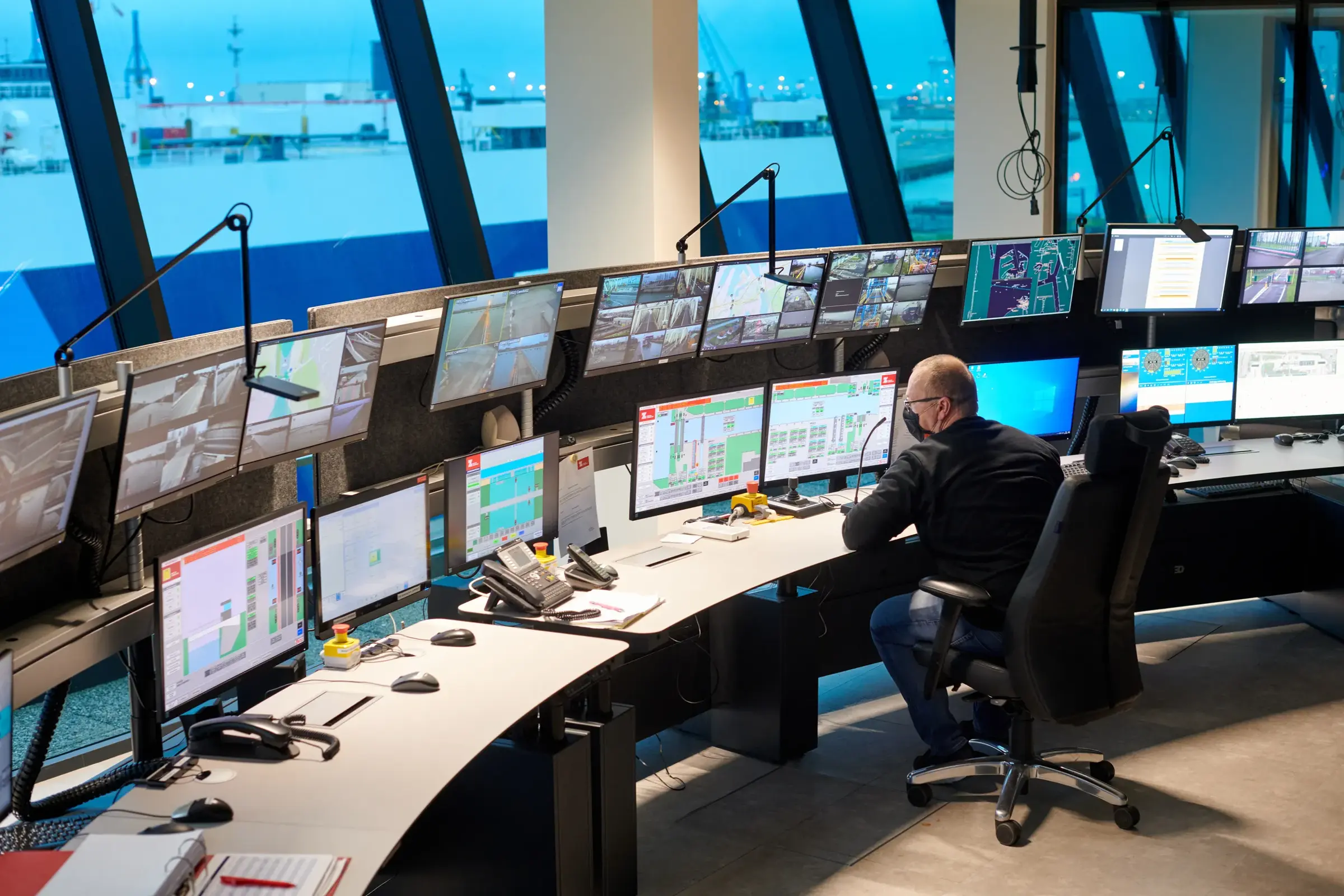 Een werknemer monitort de activiteiten in de haven aan de hand van hoogtechnologische systemen. 